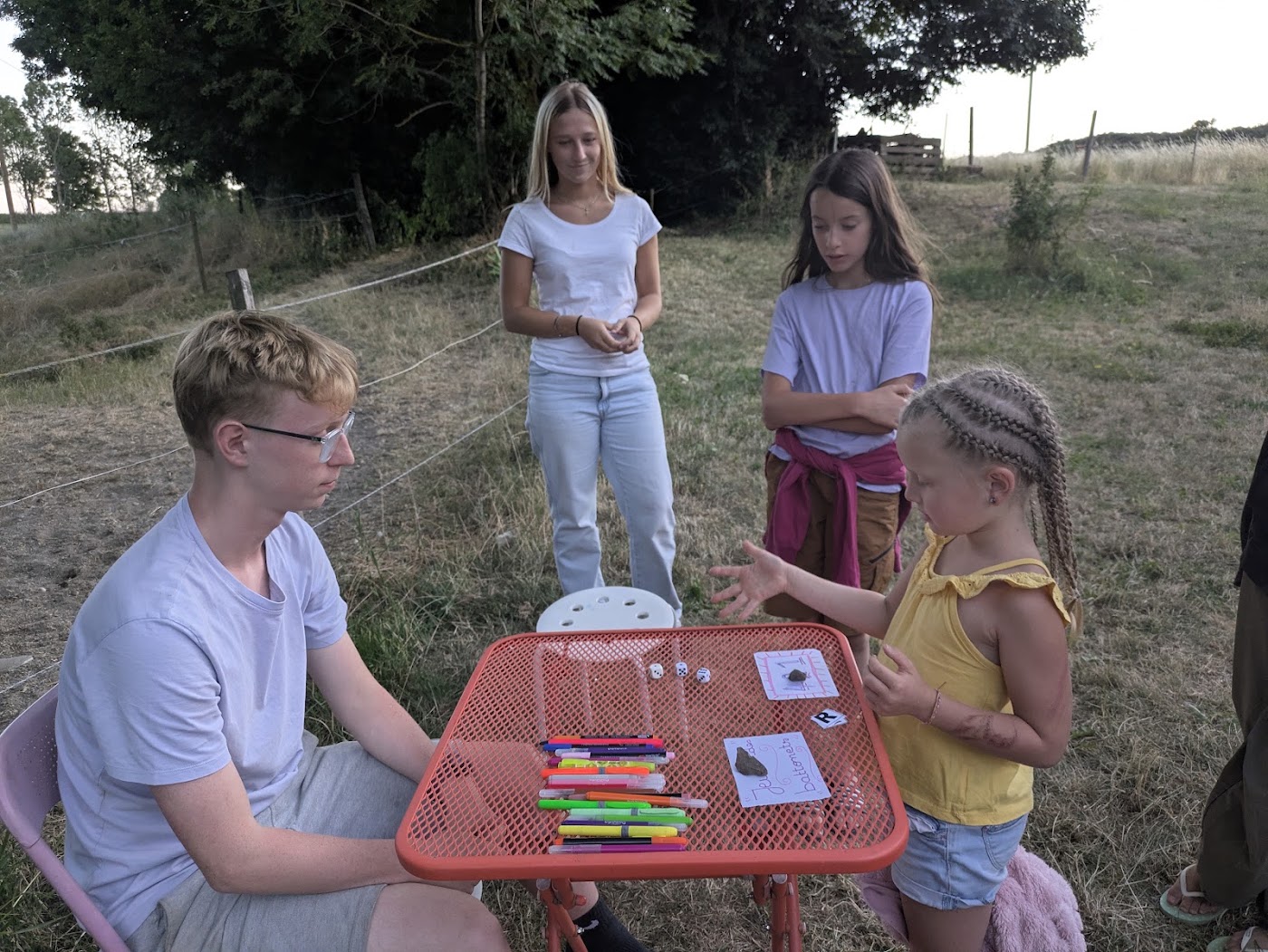 Atelier de création en plein air, enfants autour d'une table avec des feutres