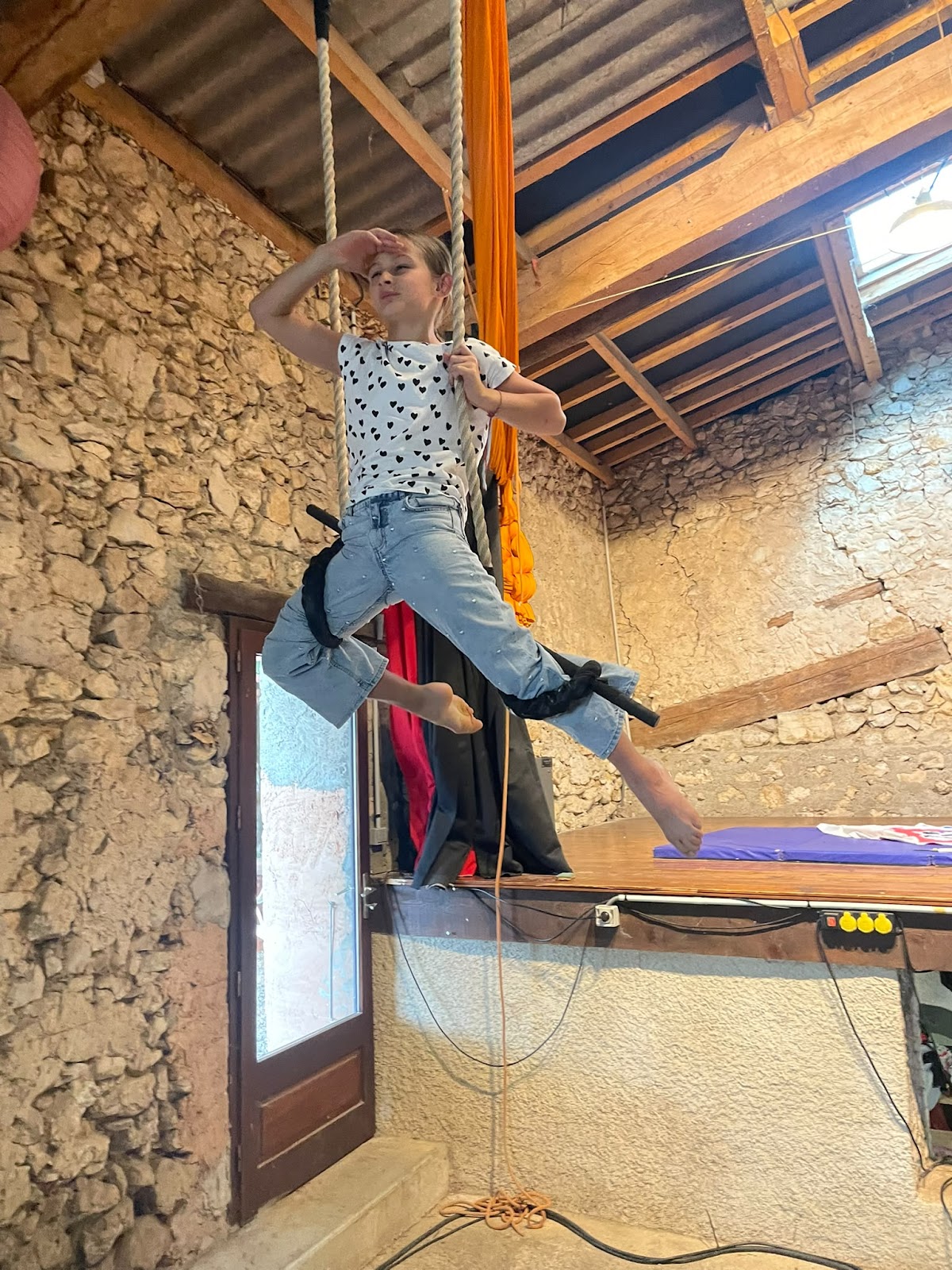 Atelier arts du cirque : une enfant en équilibre sur une corde suspendue au-dessus de la scène