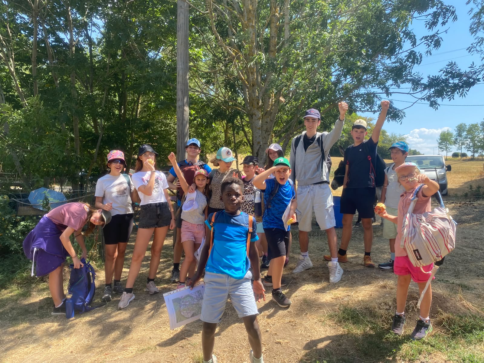 Le groupe d'enfants de la colo, tout sourire et bras levés, de retour d'une randonnée au domaine Les Vigouroux