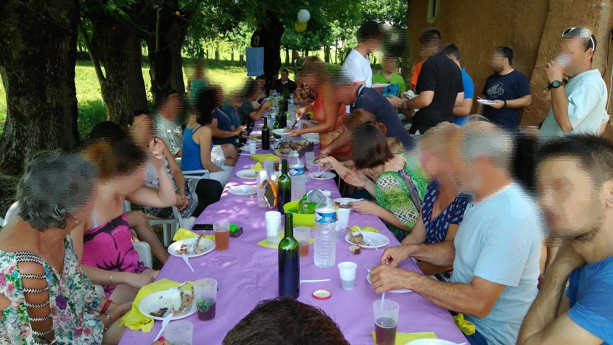 Un long repas de groupe dressé à l'ombre des arbres
