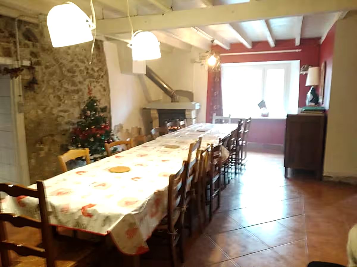 La salle à manger en longue tablée devant la cheminée, dressée pour les fêtes